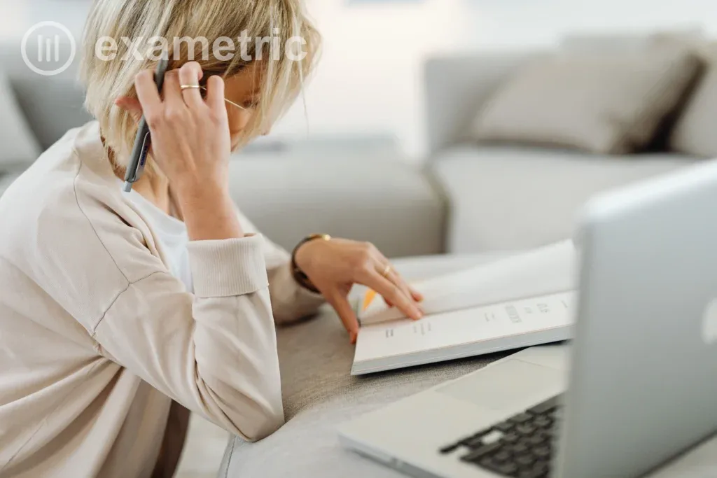 Coordenadora pedagógica analisando dados educacionais em laptop com livro e caneta ao lado, luz natural